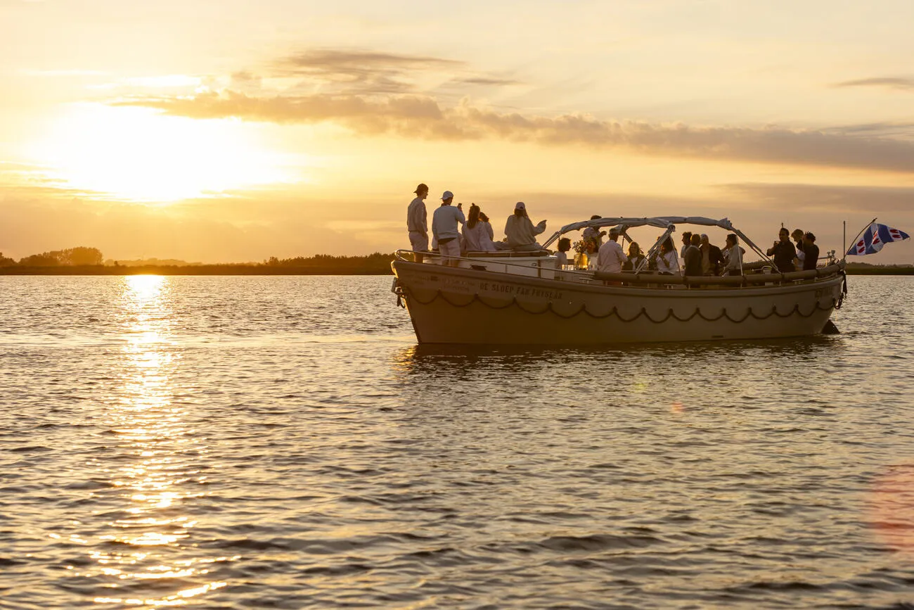 De Sloep fan Fryslân vaart bij gouden zonsondergang over het Friese water