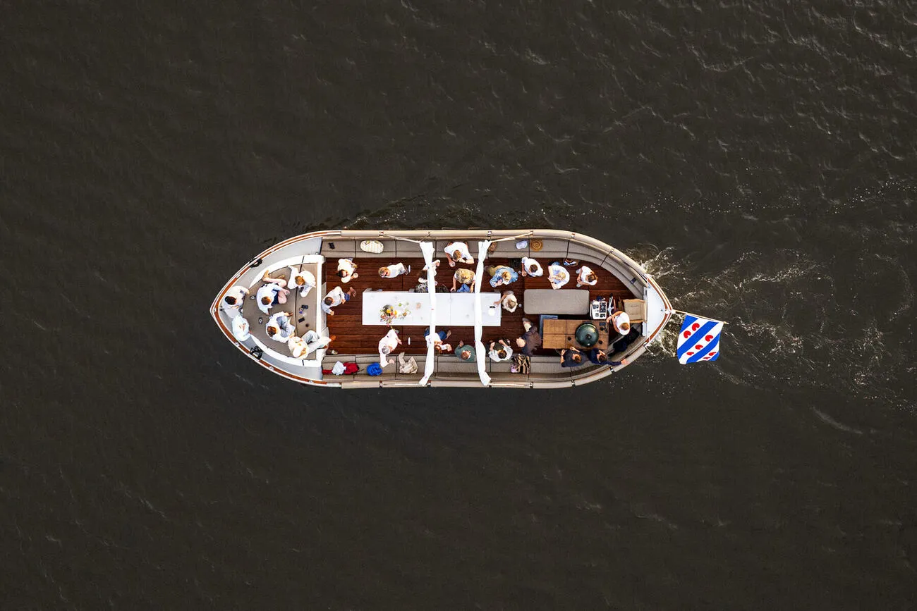 Bovenaanzicht van de sloep met gedekte tafel en gezelschap aan het diner