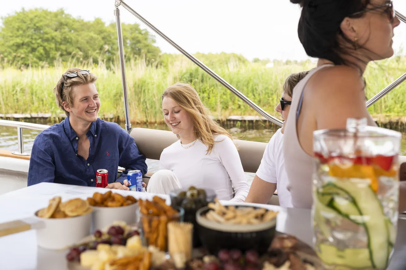 Jonge gasten met hapjes en drankjes aan boord