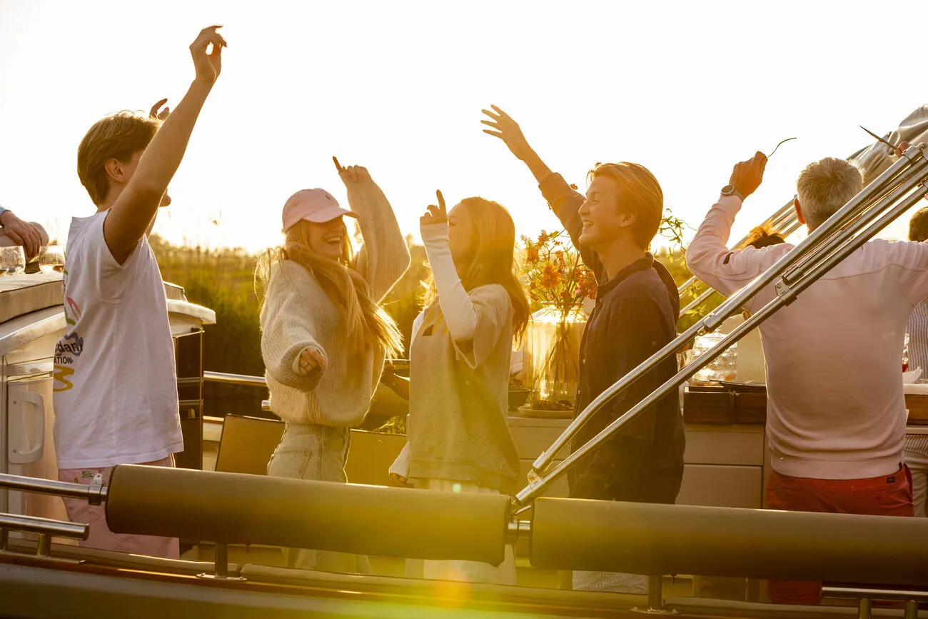 Gasten dansen aan boord in het gouden avondlicht