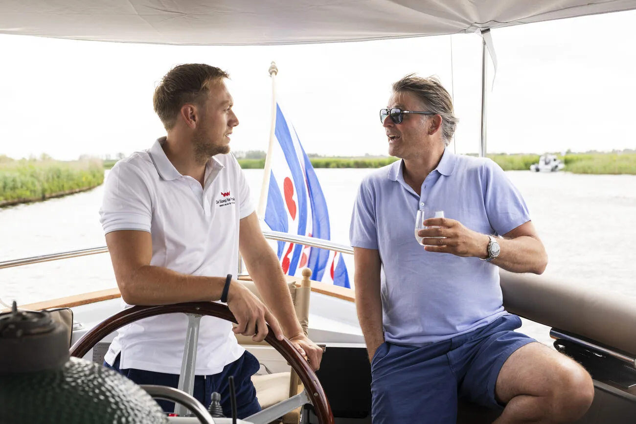 De schipper in gesprek met een gast bij de Friese vlag