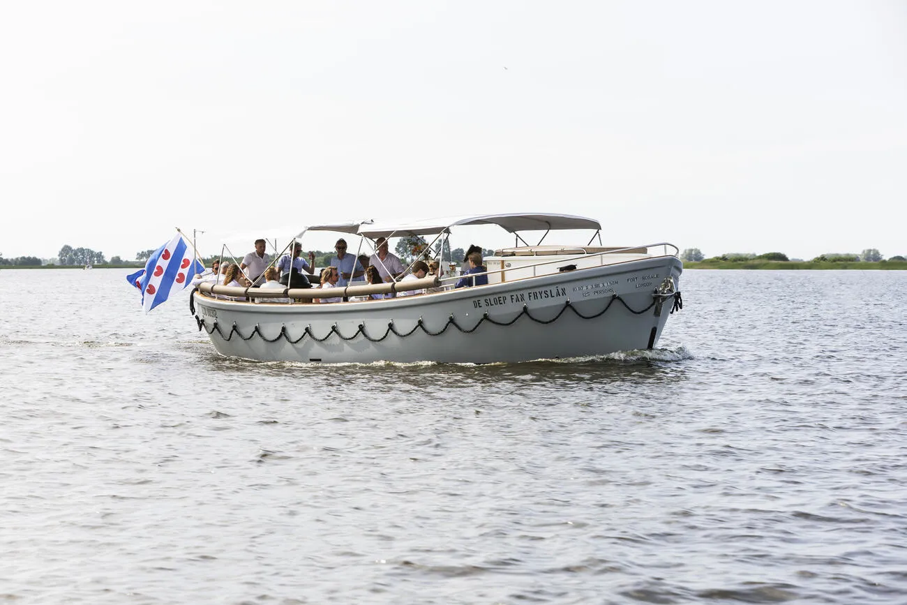 De sloep vaart met gasten over het Friese water