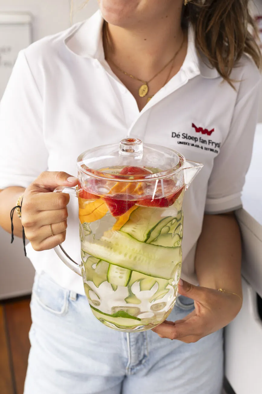 Vers bereide infused water met aardbei, sinaasappel en komkommer aan boord