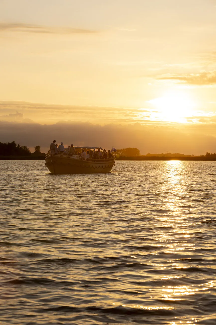 Silhouet van de sloep met gezelschap op het water bij zonsondergang