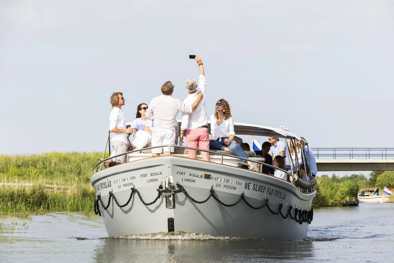 Gasten maken een selfie op de boeg van de varende sloep