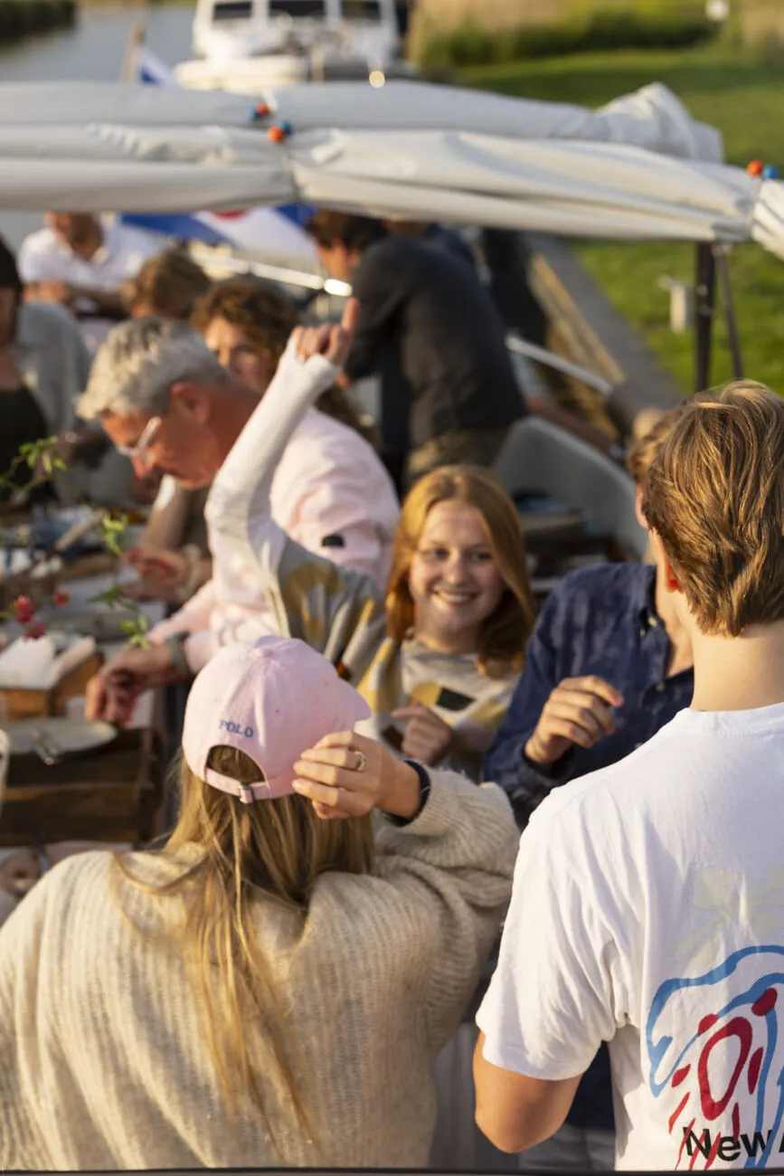 Feestend gezelschap onder de overkapping aan boord in het avondlicht